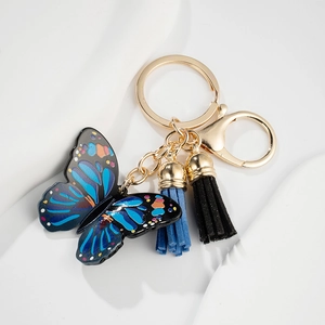 Detailed close-up of blue enamel butterfly keychain with elegant leather tassel charms