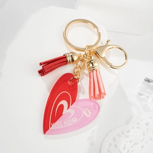 Détail du porte-clés coeur rose et rouge avec texte KISS ME et glands en cuir