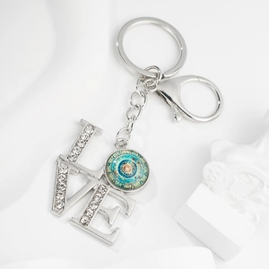 Detailed macro of silver LOVE keychain with mandala glass gem and white rhinestones