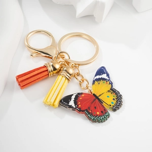 Détail d'un porte-clés papillon coloré avec des pompons orange et jaunes sur anneau