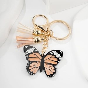 Detail of a butterfly keychain featuring tricolor wings, tassels and gold hardware