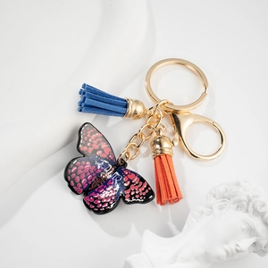 Detail of butterfly keychain with pink spotted wings, dual-tone tassels and gold hardware