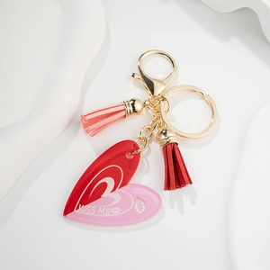 Détail du porte-clés cœur rouge et rose avec texte KISS ME et glands en cuir souple