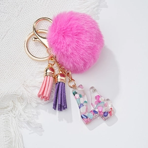 Gros plan sur le pompon en fausse fourrure rose et porte-clés lettre en résine avec fermoir doré