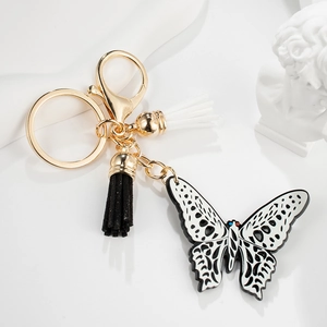 Detailed view of hollow butterfly keychain with black and white tassels on a white base
