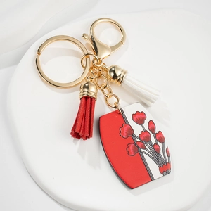 Détail d'un pendentif à fleurs avec glands rouges et blancs sur un porte-clés doré chic