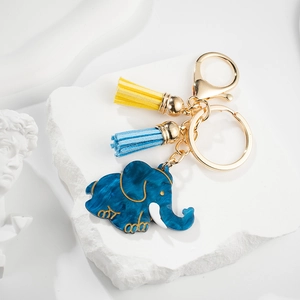 Close-up of blue marble acrylic elephant keychain with gold hardware and colorful tassels