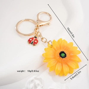 Dettaglio di un portachiavi a girasole giallo con coccinella e gancio in metallo dorato