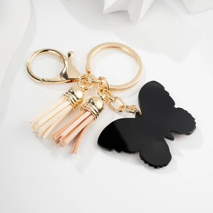 Elegant butterfly keychain with golden metal ring and stylish double tassels on white desk