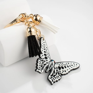 Detail of butterfly keychain with black and white tassels and golden lobster clasp