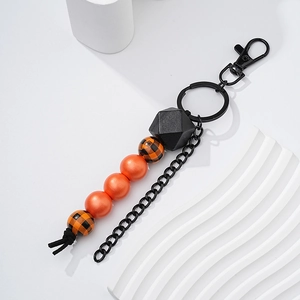Detail of beaded keychain with orange pearls and checkered wood beads on black metal ring