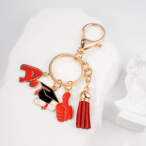 Detail of graduation keychain with A+ charm, black mortarboard, and red tassel decor