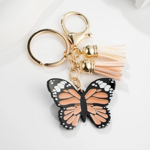 Close-up of butterfly keychain with orange wings, leather tassels and golden lobster clasp