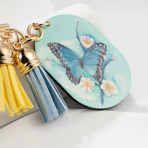 Elegant gold butterfly keychain with floral oval pendant and colorful tassels on white surface