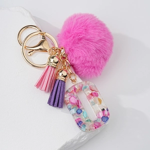 Détail d'un porte-clés pompon rose avec glands en cuir et pendentif en résine