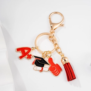 Golden graduation keychain with red A plus charm, mortarboard, and leather tassel