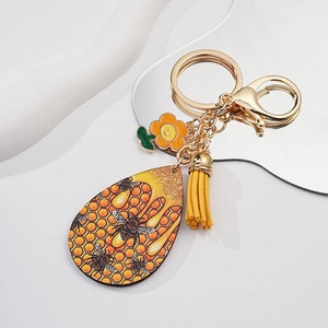 Detailed view of bee and honeycomb keychain with yellow tassel and flower charm