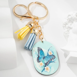 Artistic butterfly pendant keychain with blue flowers and colorful tassels in a still life view