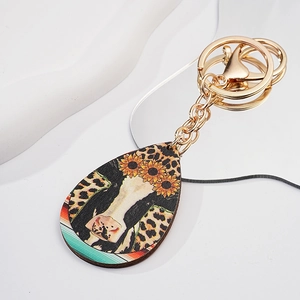 Macro view of teardrop keychain with cow pattern, sunflower print and gold metal ring