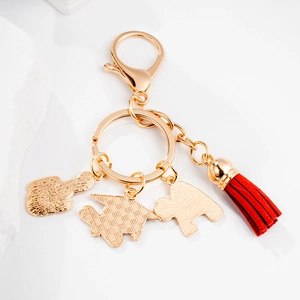 Golden doctoral cap keychain with red tassel and charms on white background