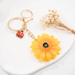 Dettaglio portachiavi a girasole con ciondolo a coccinella e anello dorato lucido
