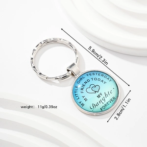 Détail macro du porte-clés argenté avec dégradé bleu et message pour sa fille