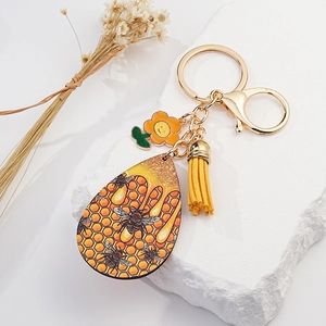 Detail of bee honeycomb keychain with yellow leather tassel and sunflower charm