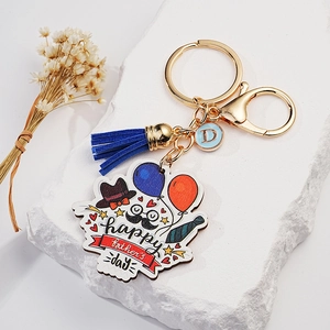 Father's Day keychain with navy tassel, blue D charm, and festive symbols on white stone
