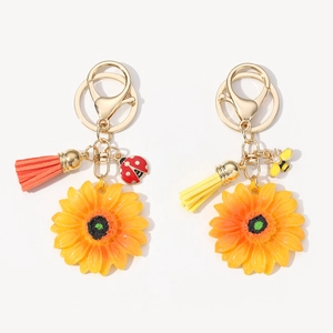 Dettaglio di portachiavi a girasole con anello in metallo, nappa in pelle e ciondoli ape