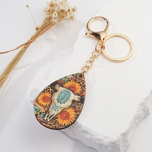 Detail of bohemian bull skull keychain with sunflower print on stone background