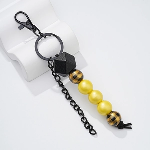 Close-up of wooden bead keychain with yellow and buffalo plaid beads on a white stand