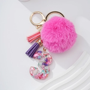 Détail du pompon rose duveteux et breloque chiffre 3 en résine avec pierres colorées