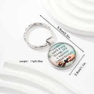 Macro shot of silver metal keychain with glass pendant featuring friendship quote