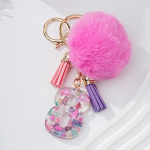 Détail macro du porte-clés chiffre 8 en résine avec pierres, pompon rose et frange