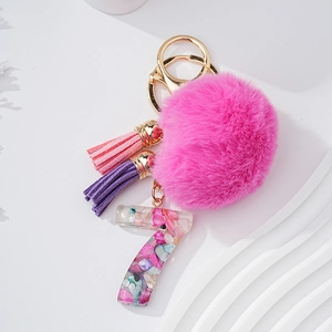 Détail d'un pompon en fourrure rose avec pendentif chiffre 7 en résine et pierres
