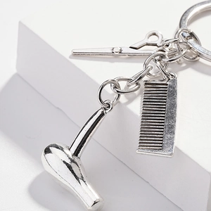Creative silver barber keychain set featuring a mini hair dryer, comb, and scissors pendant