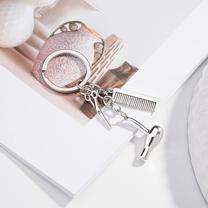 Detail of silver creative barber keychain featuring a mini comb, scissors, and hair dryer