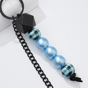 Detail of wooden beaded keychain featuring blue spheres and plaid patterns with metal ring