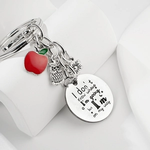Détail d'un porte-clés cadeau enseignant avec pomme rouge, hibou et disque rond gravé