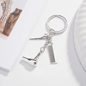 Detail of creative hair salon keychain featuring silver scissors, comb, and hair dryer charms