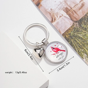 Détail du porte-clés oiseau cardinal avec pendentif cœur et texte commémoratif