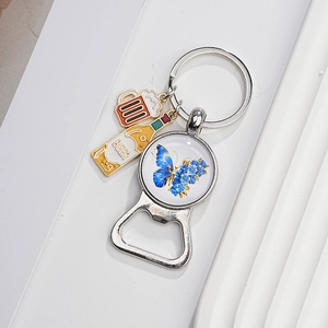 Detail of vintage metal keychain bottle opener with blue butterfly pendant and beer charms