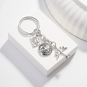 Travel keychain detail with engraved suitcase world globe and airplane charms