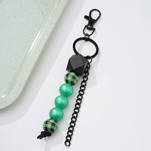 Detail of wooden beaded keychain with green plaid and matte black geometric beads