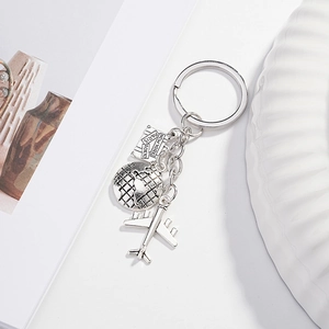 Silver travel keychain featuring airplane, world map globe, and city name tags on white
