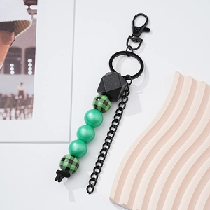 Detail of wooden beaded keychain with green beads, checkered patterns and black metal ring