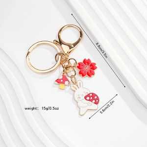 Cute bunny keychain with cherry blossom and mushroom charms on a gold lobster clasp