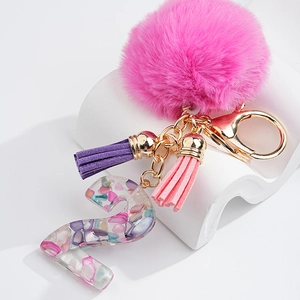 Détail du porte-clés lettre Z en résine avec pierres, pompon rose et franges violettes