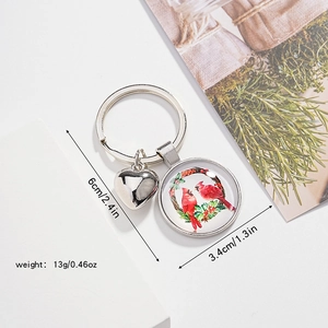 Détail d'un porte-clés argenté avec breloque oiseau cardinal rouge et pendentif cœur poli