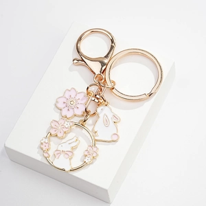 Detail of cute white rabbit keychain with pink cherry blossom charms and gold alloy finish